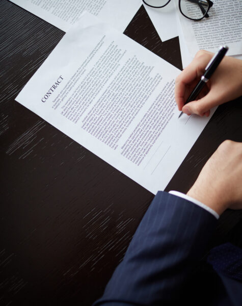 Image of businessman hand with pen signing contract at workplace