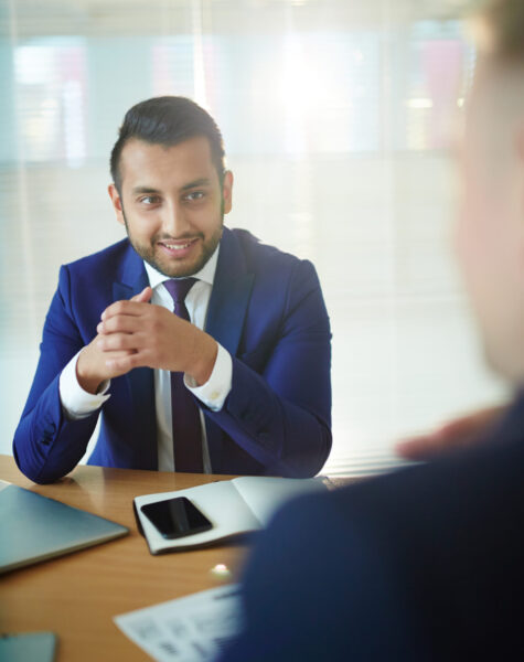 Smiling businessman in formalwear looking at colleague during conversation at working meeting